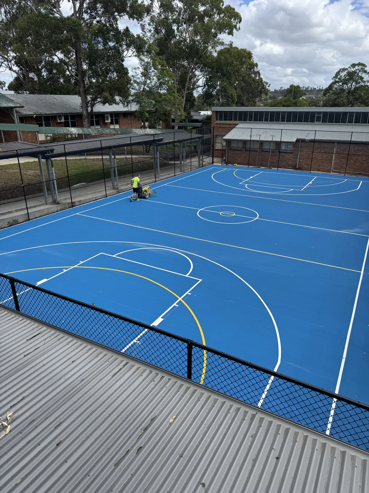 Blue acrylic basketball court being line-marked at a school — JL Turf Group