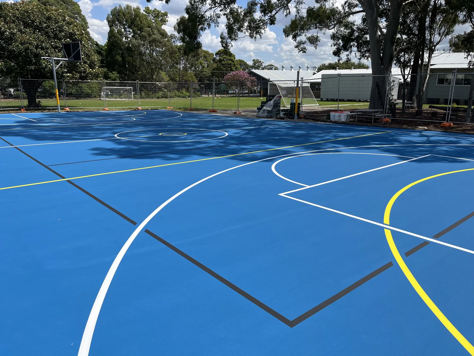 Blue acrylic multi-sport court under construction at a school — JL Turf Group
