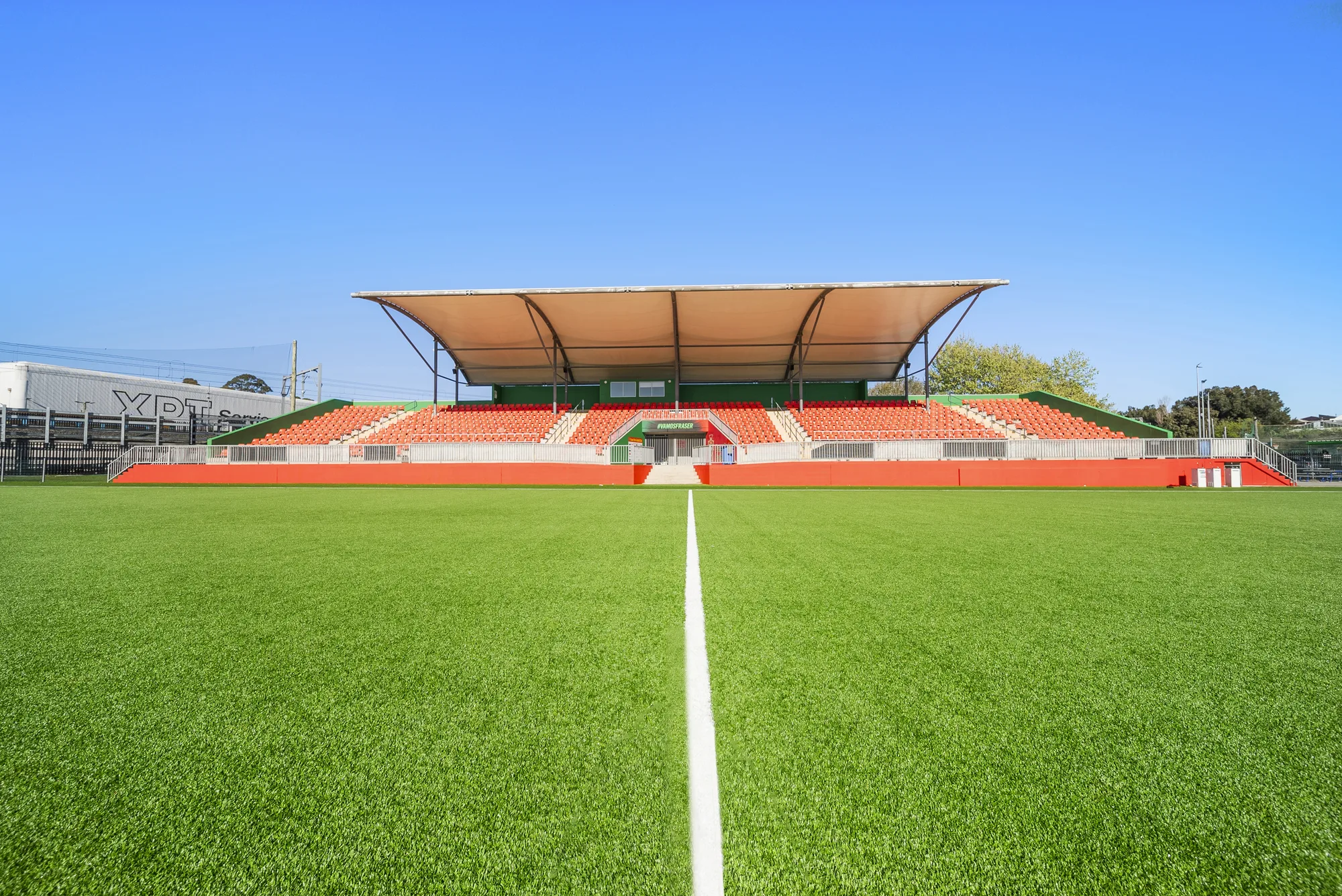 Fraser Park grandstand and orange seating behind the JL Turf Group synthetic football pitch in Marrickville